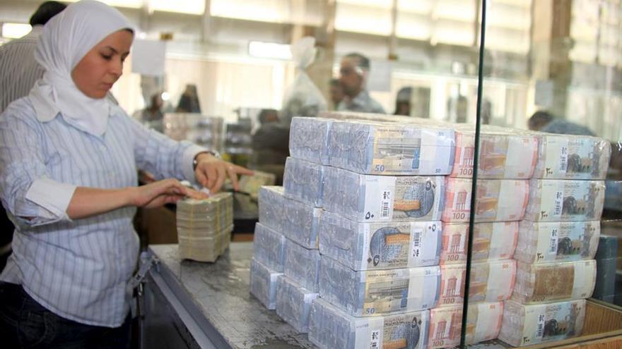 Una mujer empaca distintos tipos de billetes sirios.