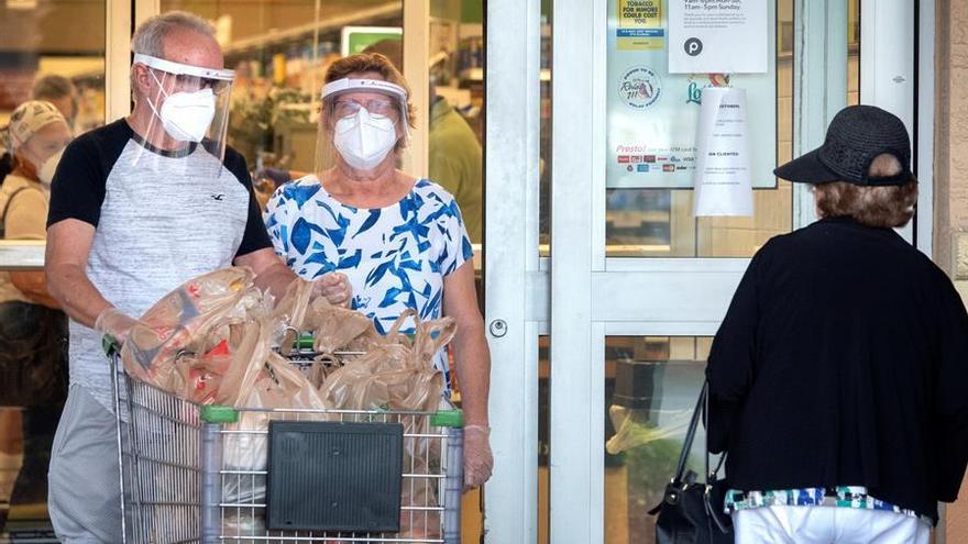 Una pareja de adultos salen de un supermercado.