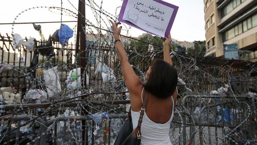 Activistas libaneses del movimiento "You Stink" tratan de quitar una barricada de alambre de púas durante una protesta frente al Palacio de Gobierno, Beirut, Líbano