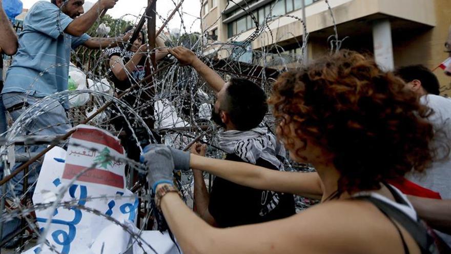 Activistas libaneses del movimiento "You Stink" tratan de quitar una barricada de alambre de púas durante una protesta frente al Palacio de Gobierno, Beirut, Líbano