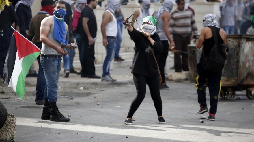 Lanzadores de piedras palestinos cubiertos, durante los enfrentamientos con las fuerzas de seguridad israelíes en Beit El, cerca de la ciudad cisjordana de Ramallah el 10 de octubre de 2015.