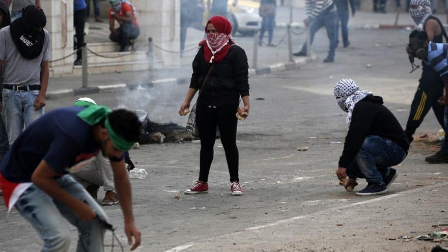 Lanzadores de piedras palestinos cubiertos, durante los enfrentamientos con las fuerzas de seguridad israelíes en Beit El, cerca de la ciudad cisjordana de Ramallah el 10 de octubre de 2015.
