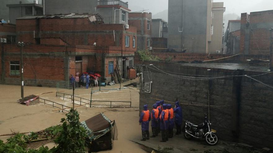 Vehículos y residentes hacen su camino a través de una calle inundada en Wenling, en la provincia oriental china de Zhejiang, el 10 de agosto 2015, después que fuertes tormentas golpearon el área durante la recalada del tifón Soudelor.