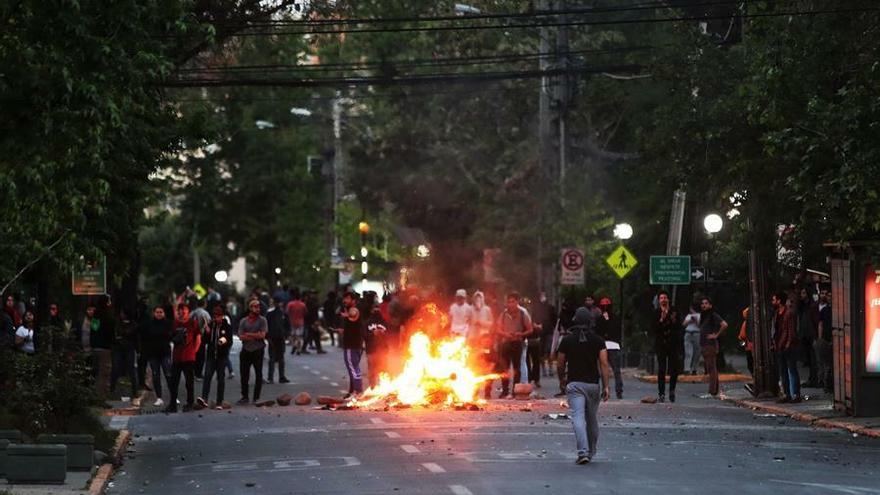 Manifestantes prende fuego a una barricada en una calle del barrio de Providencia, en el este de Santiago (Chile), este domingo durante el toque de queda decretado para la tarde y noche.