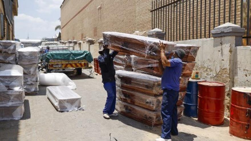Trabajadores de una funerario en Sudáfrica preparan las cajas mortuorias que serán usadas