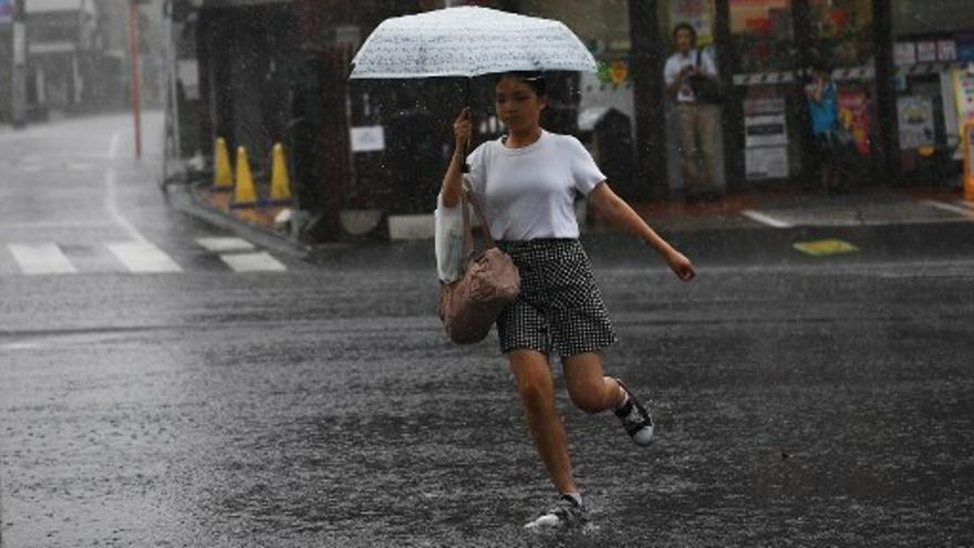 Una joven se cubre con un paraguas por la lluvia