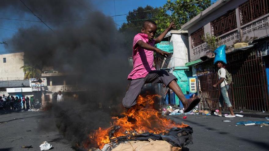 Un niño salta una barricada en llamas cerca del mercado de Petionville, durante una jornada de protestas este jueves, en Puerto Príncipe (Haití).