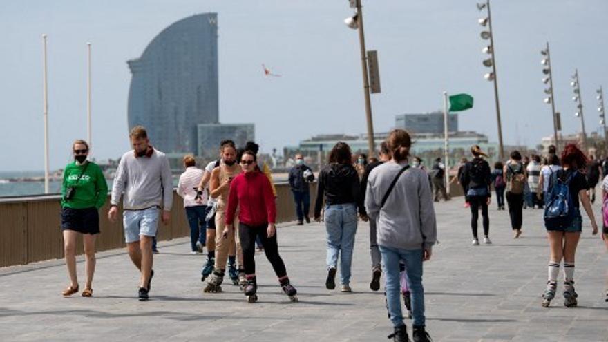 Personas caminan cerca de la playa en Barcelona.