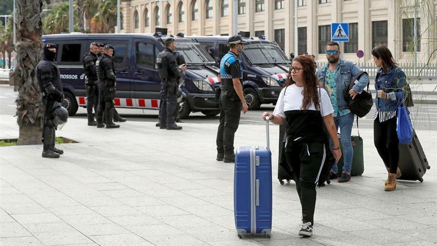 Varios turistas llegan caminando a la terminal de cruceros del Puerto de Barcelona, fuertemente custodiada por los mossos d'esquadra después de que un grupo de manifestantes tratara de acceder por la fuerza, el pasado viernes.