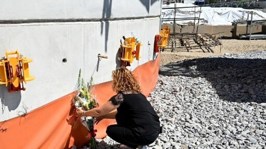 Una mujer deposita un ramo de flores frente al nuevo pilón del puente después de la misa por el primer aniversario de la caída del puente de Morandi, en Génova.