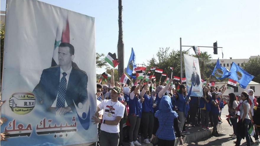 Un grupo de jóvenes exhibe banderas y retratos del presidente, Bachar Al Asad.