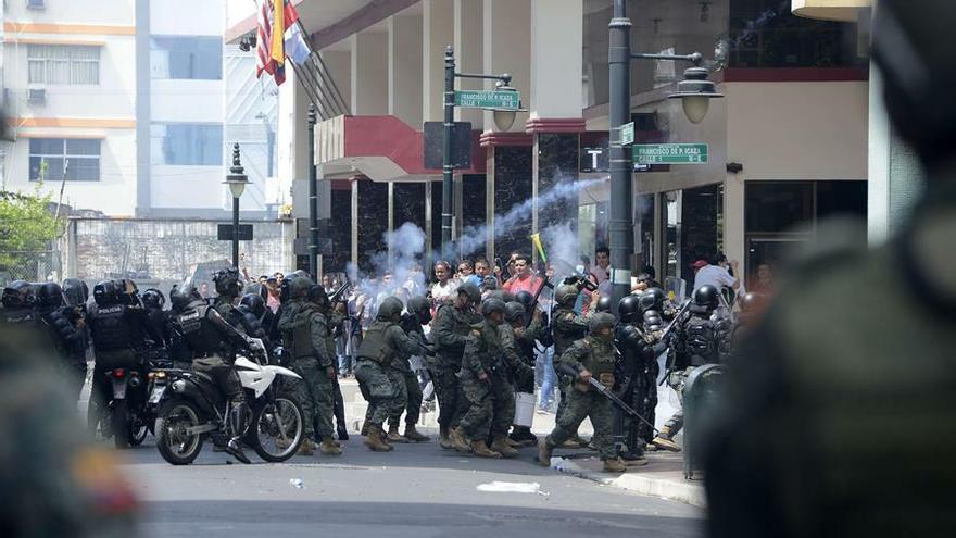 Decenas de personas se enfrentan a la policía antidisturbios, mientras se celebra una concentración para pedir paz en el país, este miércoles, en Guayaquil (Ecuador).