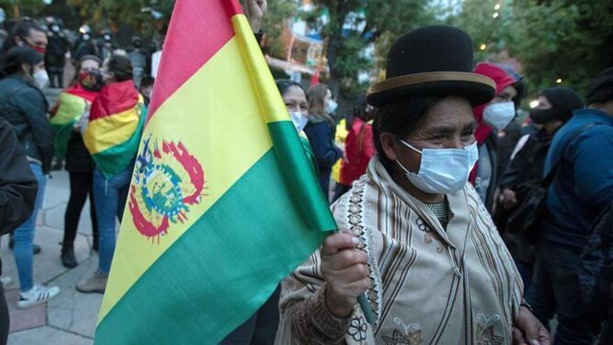Mujer boliviana cargando una bandera.
