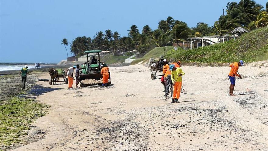 Trabajadores intentan contener y limpiar las manchas de petróleo que contaminan la playa Lagoa do Pau este jueves, en el municipio de Coruripe, estado Alagoas (Brasil).