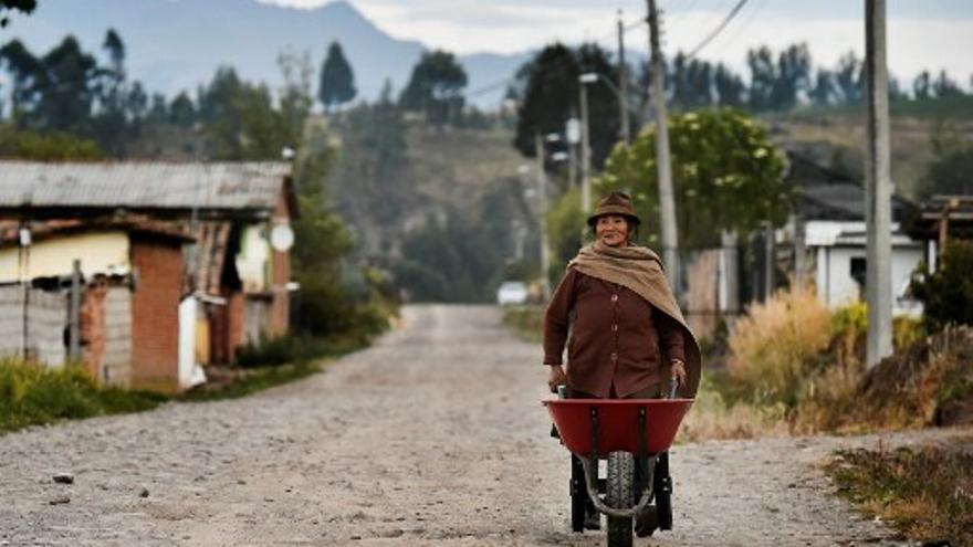 Una indígena lleva una carretilla por el camino de un poblado en Ecuador