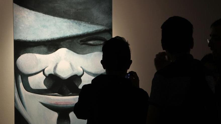 Asistentes observan un cuadro del cómic "V for Vendetta" (""V de Vendetta""), del ilustrador británico David Lloyd