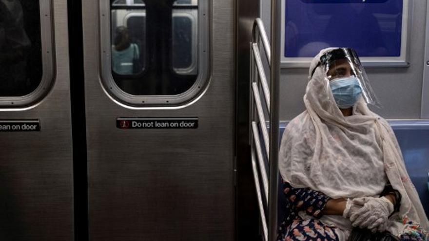 Una persona usa mascarilla y pantalla facial en el metro de Nueva York